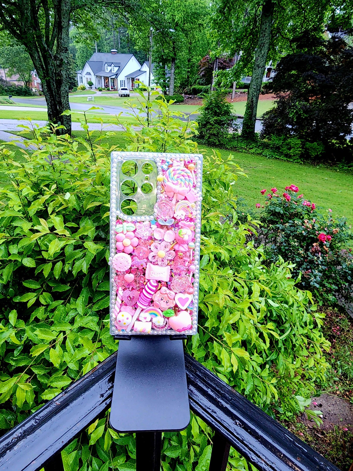 Handmade Kawaii Pink Candy Decoden Phone Case with cute candy-themed charms displayed outdoors.